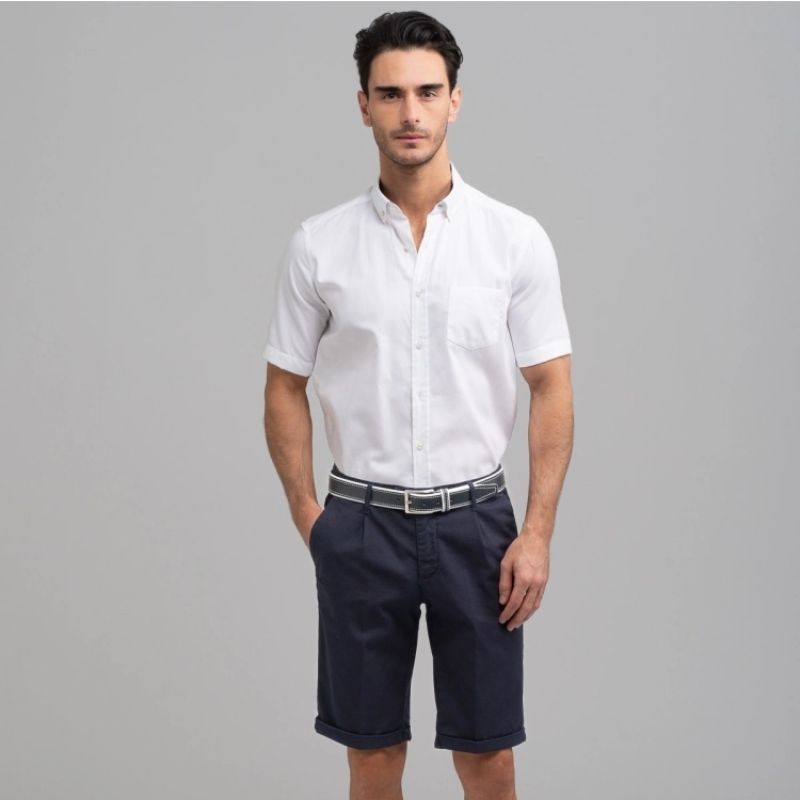 Ragazzo che indossa camicia bianca a maniche corte con collo button down e bermuda modello chino color blu